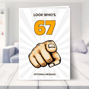 funny 67th birthday card shown in a living room