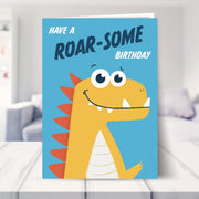 dinosaur birthday card shown in a living room